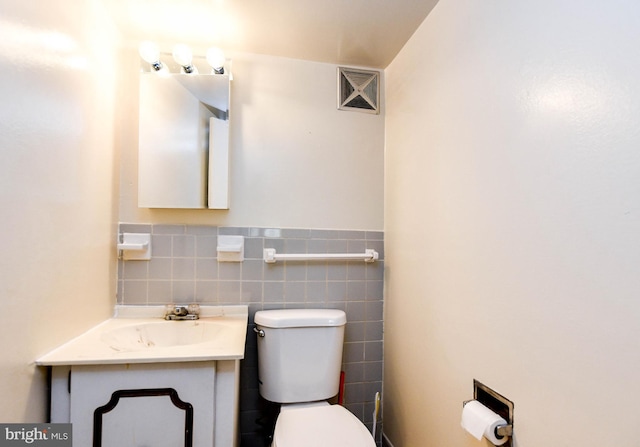 bathroom featuring vanity, toilet, and tile walls