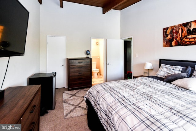 carpeted bedroom with beam ceiling, ensuite bathroom, and a towering ceiling