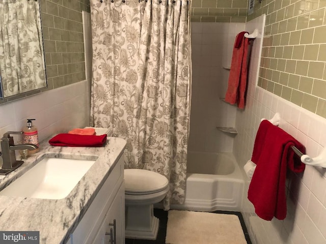 full bathroom with vanity, toilet, tile walls, and shower / tub combo