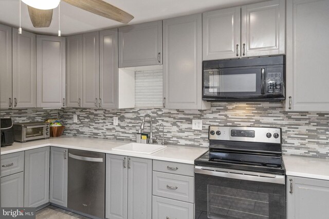 kitchen featuring appliances with stainless steel finishes, gray cabinetry, a sink, and tasteful backsplash