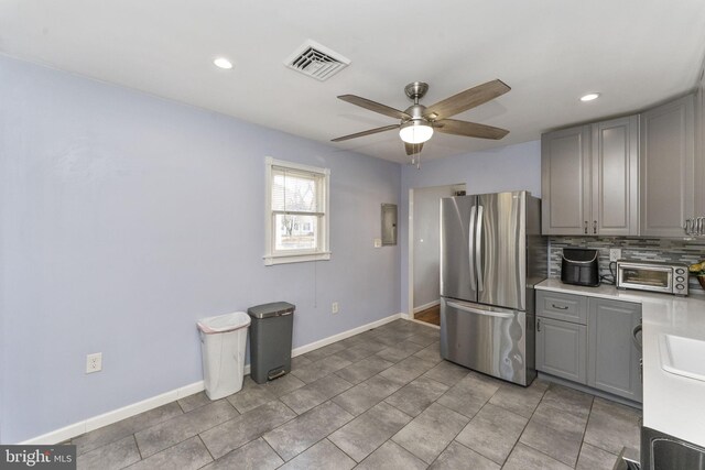 kitchen with freestanding refrigerator, gray cabinetry, a ceiling fan, decorative backsplash, and recessed lighting