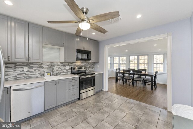 kitchen featuring appliances with stainless steel finishes, gray cabinetry, a sink, a ceiling fan, and recessed lighting