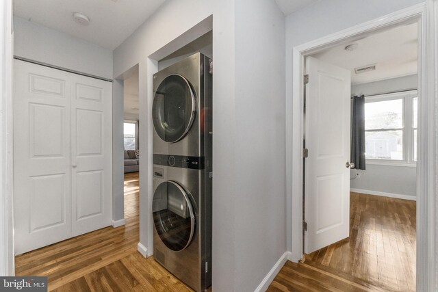 laundry room featuring estacked washer and dryer, wood finished floors, and baseboards