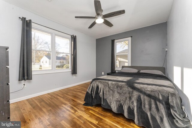 bedroom with wood finished floors, baseboards, and a ceiling fan