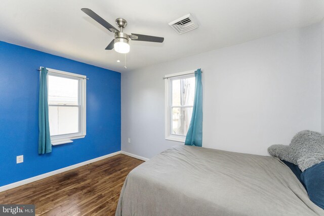 bedroom featuring dark wood-style flooring, baseboards, multiple windows, and a ceiling fan