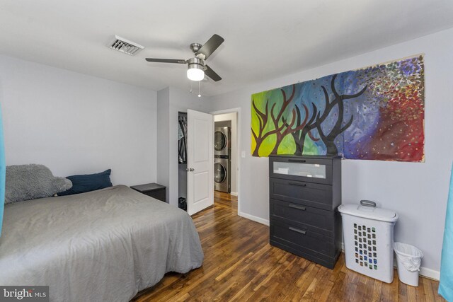 bedroom with estacked washer and dryer, wood finished floors, baseboards, and a ceiling fan