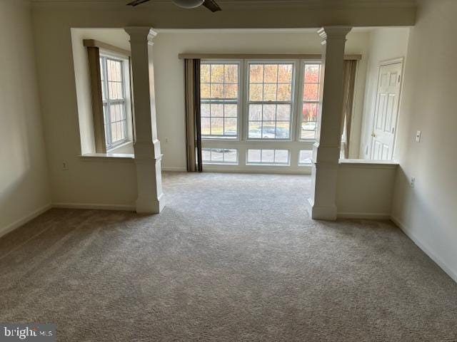 carpeted empty room with decorative columns and ceiling fan