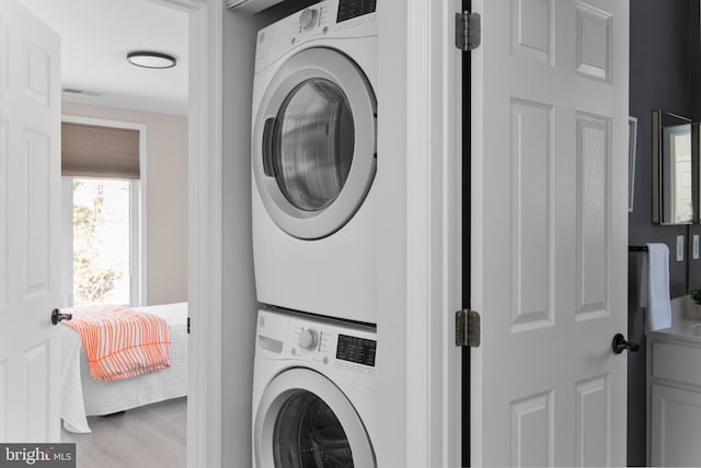 washroom featuring light hardwood / wood-style floors and stacked washer and clothes dryer