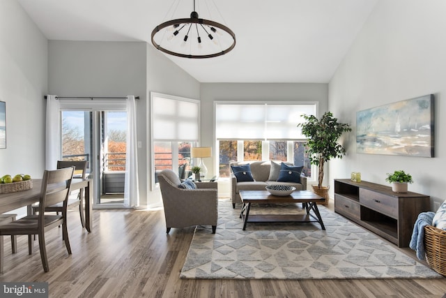 living room featuring a notable chandelier, wood-type flooring, and high vaulted ceiling