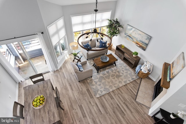 living room featuring light hardwood / wood-style floors, high vaulted ceiling, plenty of natural light, and a notable chandelier