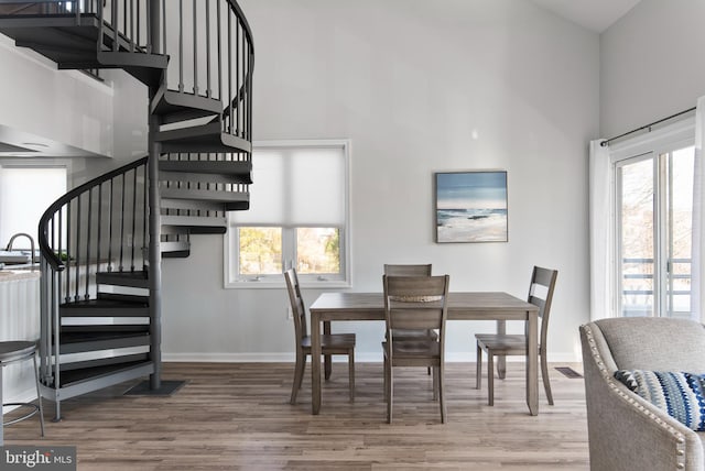 dining area with hardwood / wood-style flooring and a towering ceiling