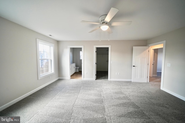 unfurnished bedroom featuring light carpet, a walk in closet, ensuite bath, and a closet