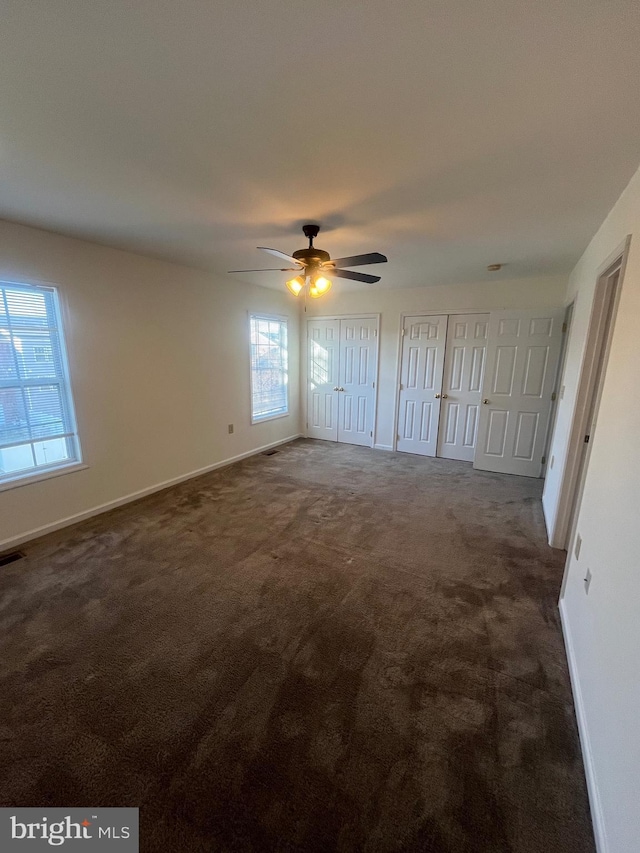 empty room featuring dark colored carpet and ceiling fan