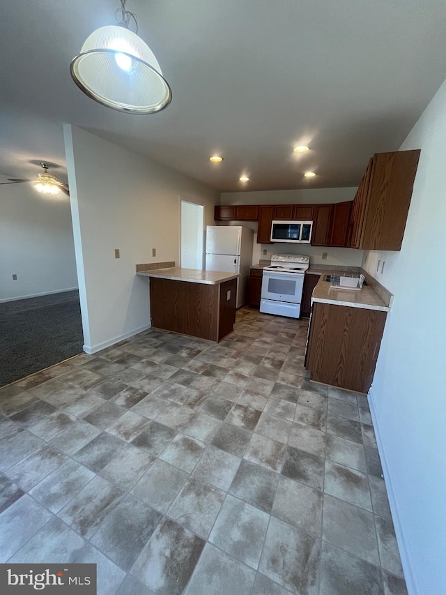 kitchen featuring white appliances, hanging light fixtures, and sink