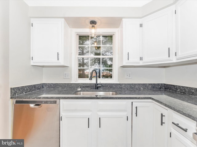 kitchen with stainless steel dishwasher, sink, dark stone countertops, white cabinets, and hanging light fixtures