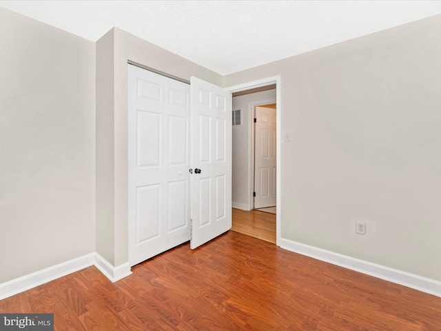 unfurnished bedroom with hardwood / wood-style flooring, a textured ceiling, and a closet