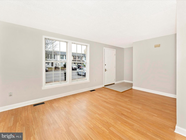 spare room with light hardwood / wood-style flooring and a textured ceiling