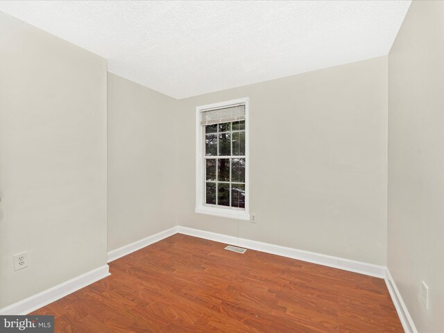 spare room featuring hardwood / wood-style floors and a textured ceiling