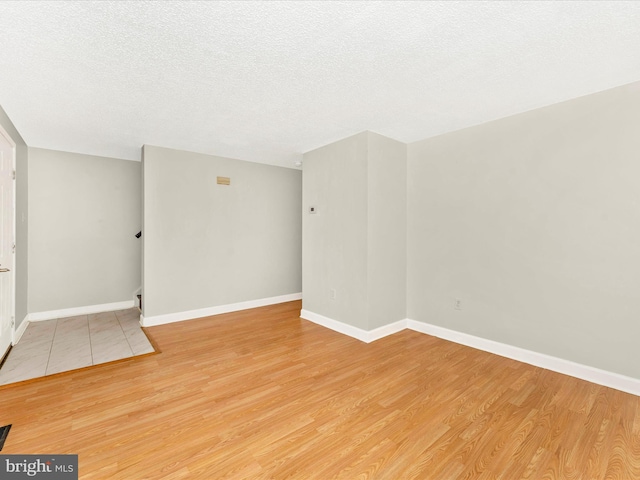 spare room featuring light hardwood / wood-style floors and a textured ceiling