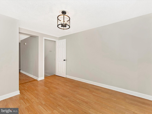 interior space with a chandelier, a textured ceiling, and light wood-type flooring