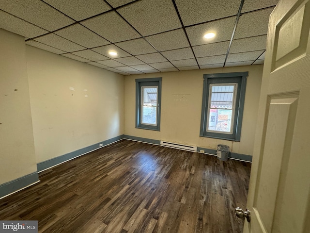 spare room featuring plenty of natural light, a drop ceiling, dark wood-type flooring, and a baseboard radiator