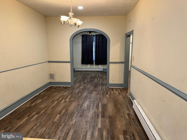 unfurnished dining area with dark wood-type flooring, an inviting chandelier, and a baseboard heating unit