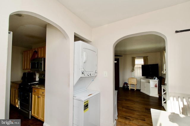 laundry room featuring dark hardwood / wood-style flooring and stacked washer and clothes dryer