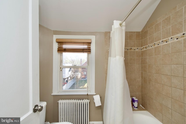 bathroom featuring shower / bath combo, vaulted ceiling, and radiator