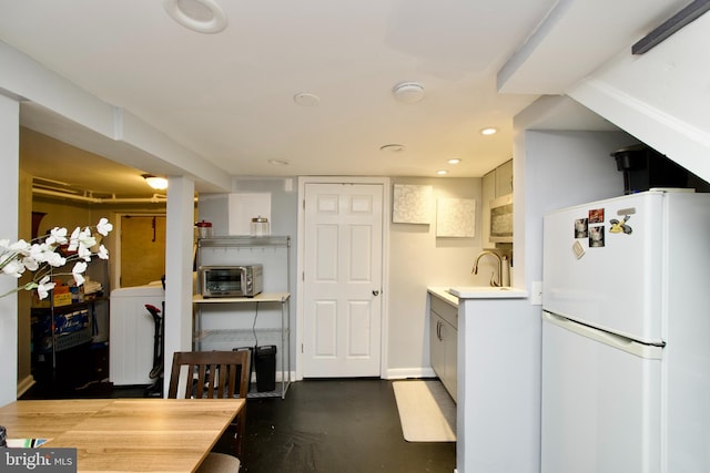 kitchen with washer / dryer, white cabinetry, sink, and white refrigerator