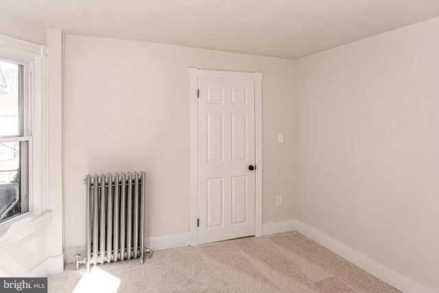 unfurnished room featuring a wealth of natural light, light carpet, and radiator