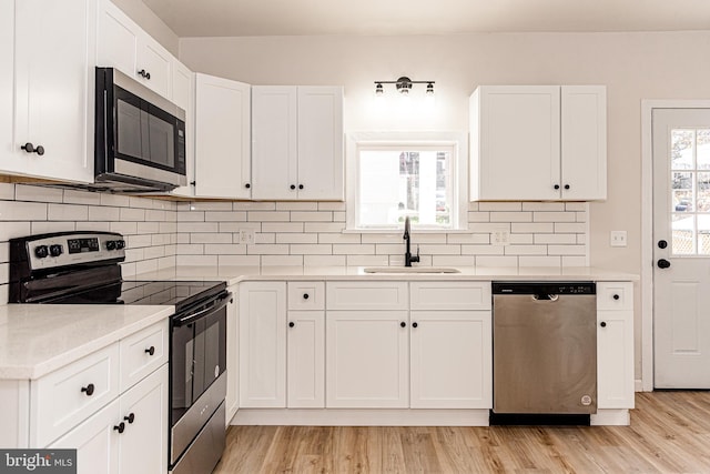 kitchen featuring white cabinetry, sink, stainless steel appliances, tasteful backsplash, and light hardwood / wood-style flooring