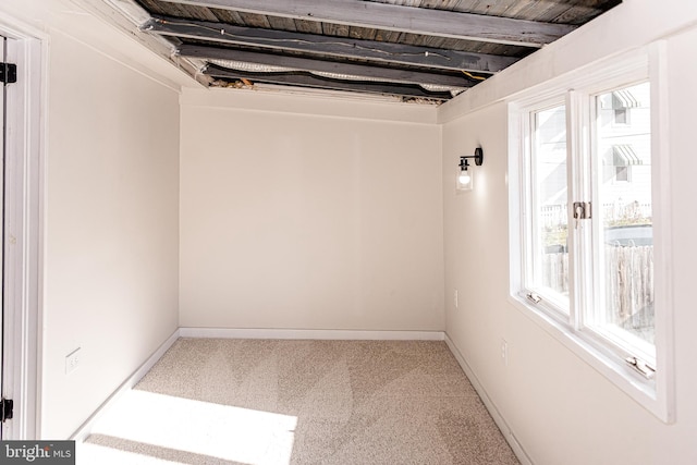 empty room with carpet flooring, beam ceiling, plenty of natural light, and wooden ceiling