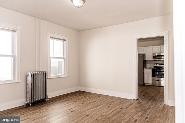 spare room featuring hardwood / wood-style flooring, a healthy amount of sunlight, and radiator