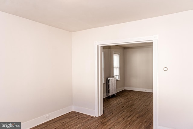 empty room featuring dark hardwood / wood-style flooring and radiator