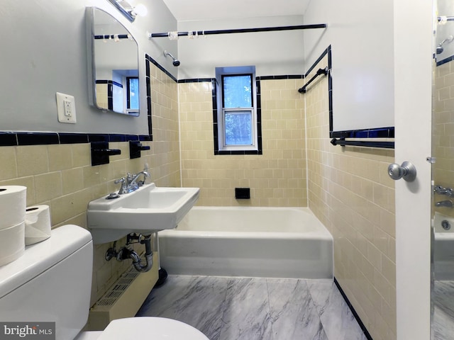 bathroom with tiled shower / bath, toilet, and tile walls