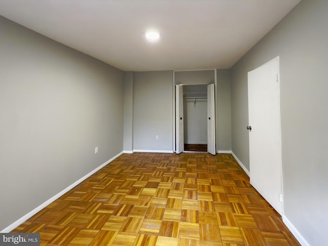 unfurnished bedroom featuring a closet and light parquet flooring