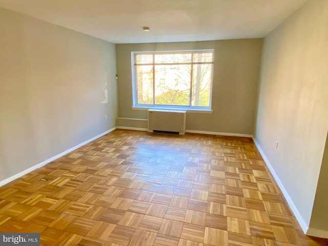 unfurnished room with radiator heating unit and light parquet flooring