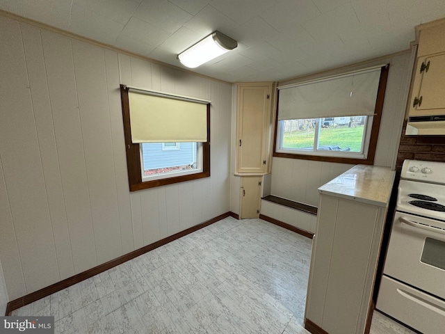 kitchen with white range with electric stovetop, plenty of natural light, wood walls, and exhaust hood