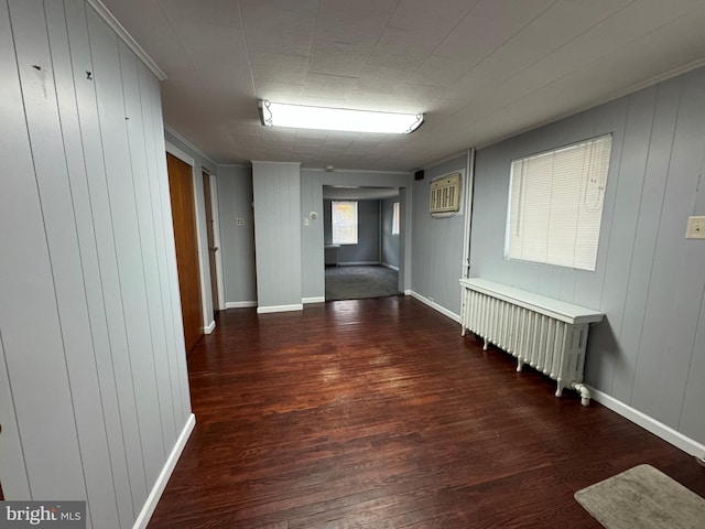 hall with dark hardwood / wood-style flooring, radiator, and wooden walls