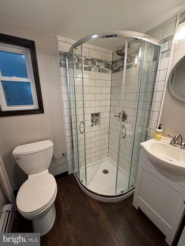 bathroom featuring vanity, wood-type flooring, a shower with door, and a baseboard heating unit