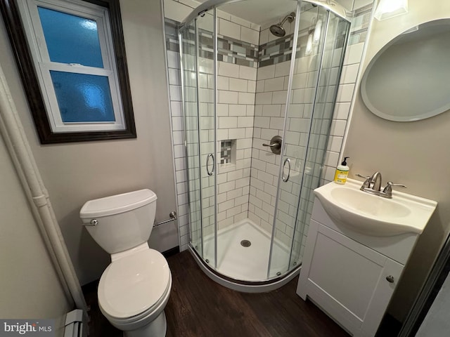 bathroom featuring vanity, a shower with door, a baseboard heating unit, hardwood / wood-style floors, and toilet