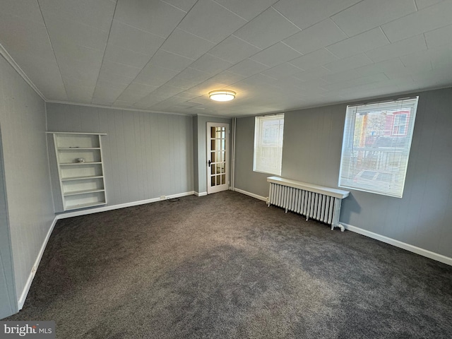 spare room featuring dark colored carpet and radiator