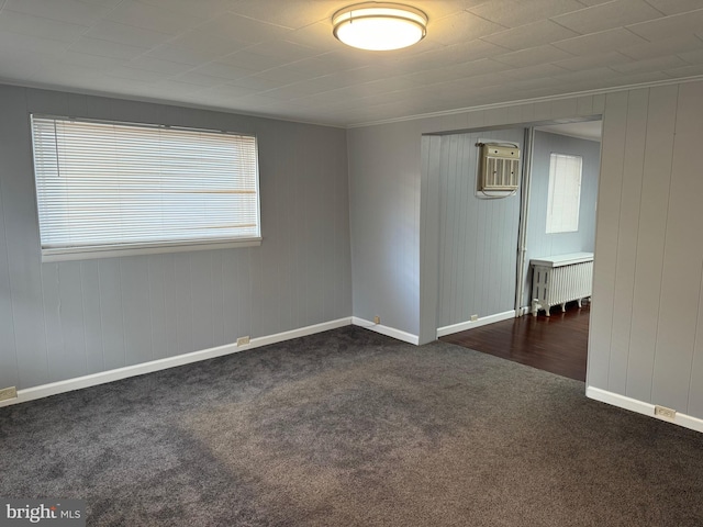 empty room featuring crown molding, radiator heating unit, and dark carpet