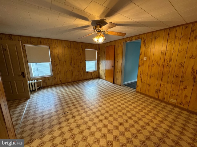 spare room featuring radiator, plenty of natural light, and wood walls