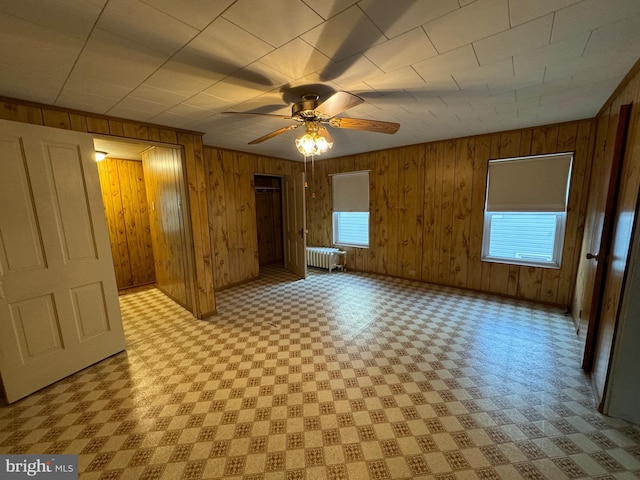 interior space with wooden walls, ceiling fan, and radiator