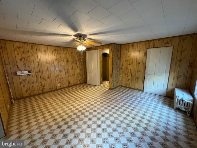 interior space with ceiling fan and wood walls