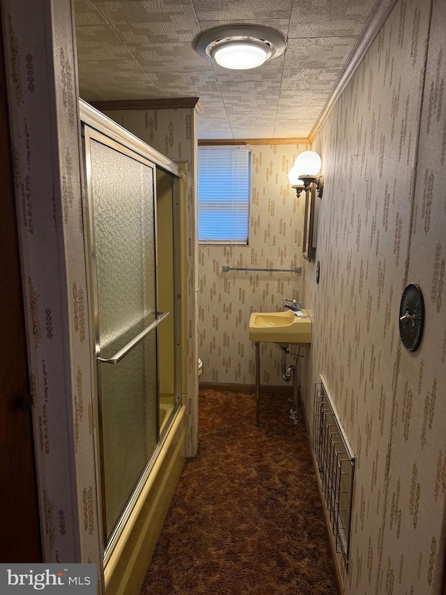 full bathroom with sink, combined bath / shower with glass door, toilet, and crown molding