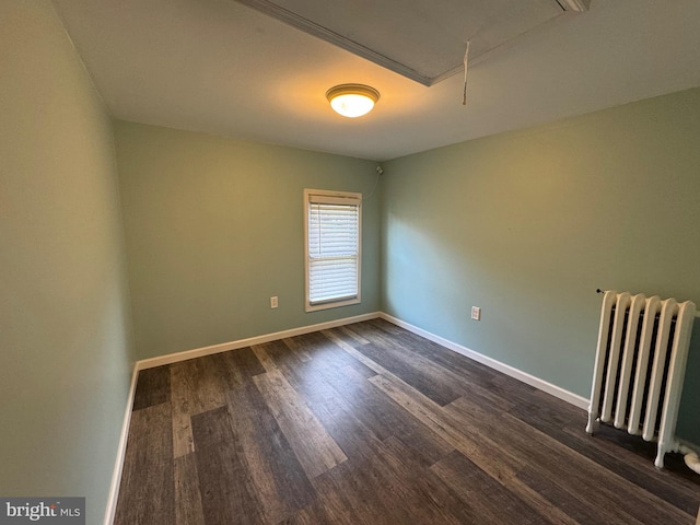 unfurnished room featuring dark hardwood / wood-style flooring and radiator heating unit