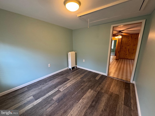 spare room with radiator, ceiling fan, and dark wood-type flooring