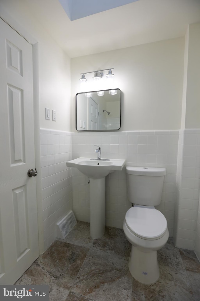 bathroom featuring toilet and tile walls